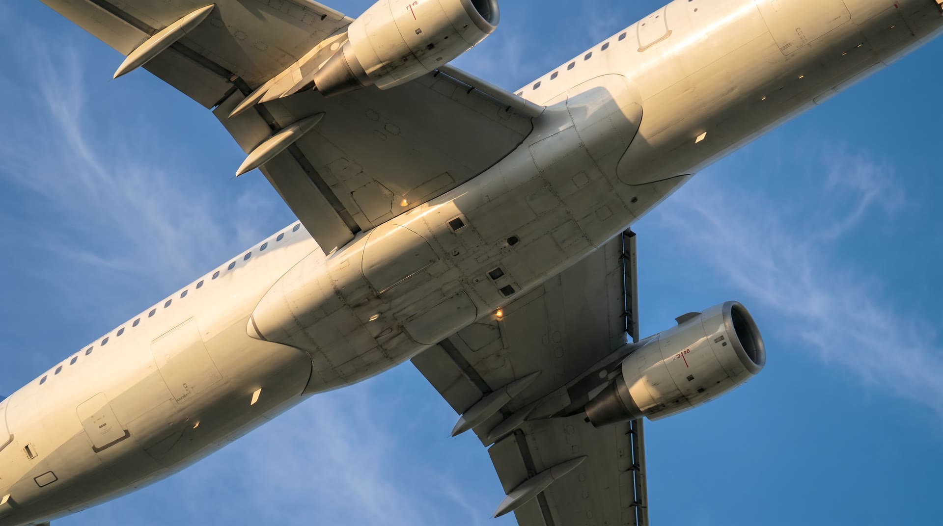 The underside of an airliner climbing against a clear sky