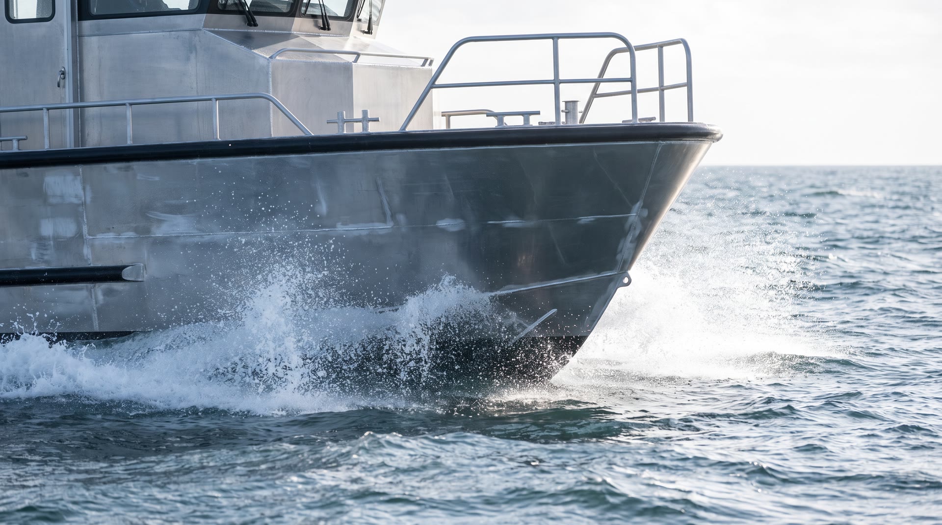 The bow of an aluminium workboat throwing spray